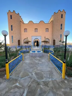 a large brick building with a fountain in front of it at Palm Garden in Erfoud