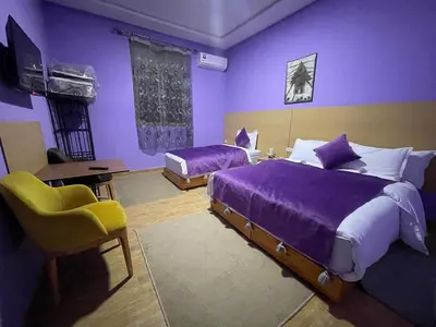 a purple bedroom with two beds and a chair at Palm Garden in Erfoud