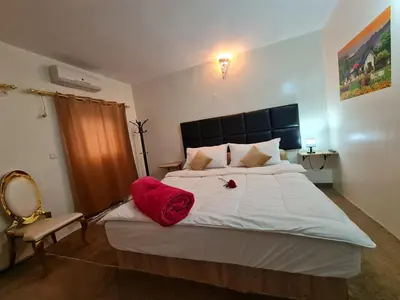 a bedroom with a large bed with a red blanket on it at Hôtel et Restaurant ARIJ in Midelt