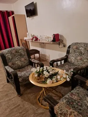 a living room with two chairs and a table with flowers on it at Hôtel et Restaurant ARIJ in Midelt