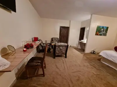 a living room with a table and chairs and a bed at Hôtel et Restaurant ARIJ in Midelt