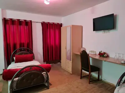 a bedroom with a bed and a desk and red curtains at Hôtel et Restaurant ARIJ in Midelt