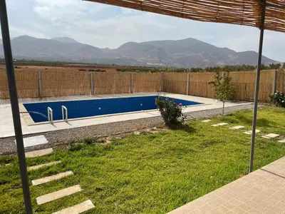 a swimming pool in a yard with mountains in the background at Ferme Jnan Al Yassmine in Taza