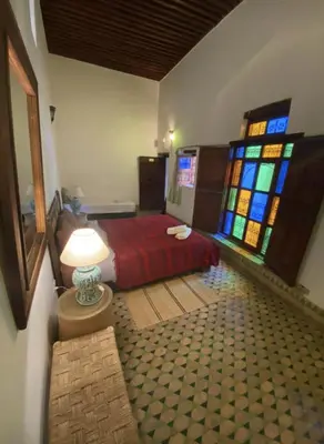 a bedroom with a bed and stained glass windows at Riad Alfredo in Fès