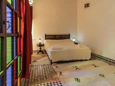 a bedroom with a white bed and a window at Riad Alfredo in Fès