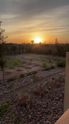 a sunset over a field with rocks and trees at Dar Amali, villa spacieuse 9ch avec piscine en exclusivité in Marrakech