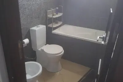 a bathroom with a white toilet and a bath tub at Luxurious apartment city center in Fès