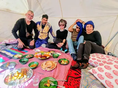 a group of people sitting in a tent with food at AUBERGE SAHARA IRIKI & Désert Tours in Foum Zguid