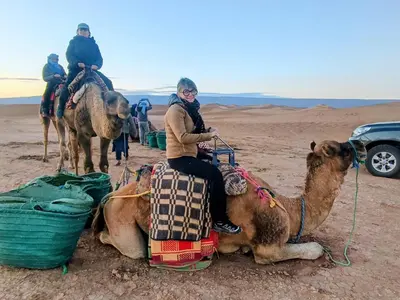 a woman sitting on a camel in the desert at AUBERGE SAHARA IRIKI & Désert Tours in Foum Zguid