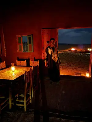 a woman standing in front of a table in a restaurant at AUBERGE SAHARA IRIKI & Désert Tours in Foum Zguid