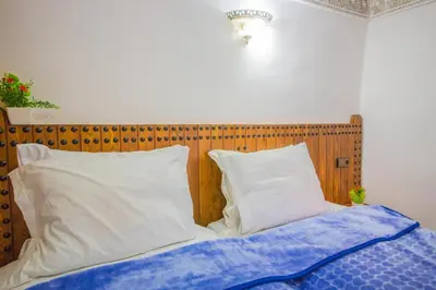 a bed with a wooden headboard and two pillows at Riad Basma Fes - Tranquil Getaway in Fès