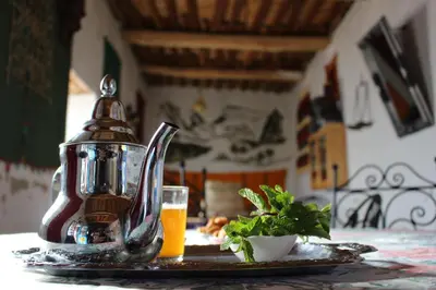 a table with a tea kettle and a glass of orange juice at Auberge Ibrahim in Agoudal