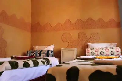 two beds in a room with orange walls at Auberge Ibrahim in Agoudal