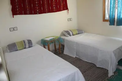 a room with two beds and a table in it at Gite Skoura in Caïd Bou Malla