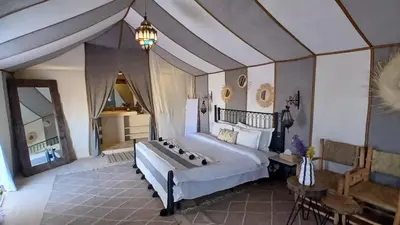 a bedroom with a large bed and a table at Sunshine luxury desert camp in Merzouga