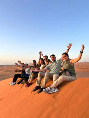 a group of people sitting on top of a sand dune at Sunshine luxury desert camp in Merzouga
