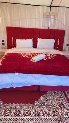 a large bed with a red headboard in a room at Sunshine luxury desert camp in Merzouga