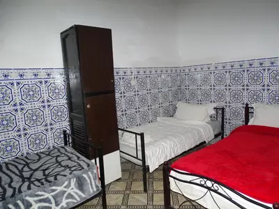 a room with two beds and a chair in it at Riad Amimi Fes in Fès