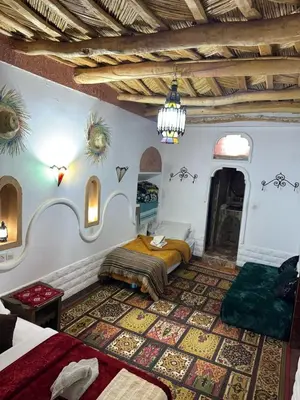 a bedroom with two beds and a chandelier at Tafsut dades guesthouse stay with locals in Tamellalt