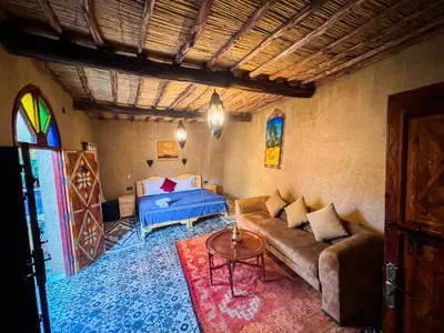 a living room with a couch and a bed at Riad le Petit Jardin in Zagora