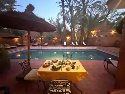a table with food on it next to a pool at Riad le Petit Jardin in Zagora