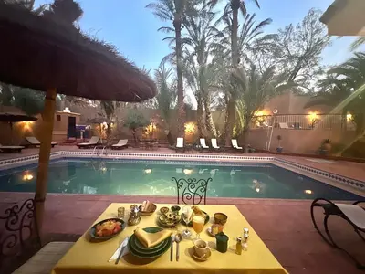 a table with food on it next to a swimming pool at Riad le Petit Jardin in Zagora