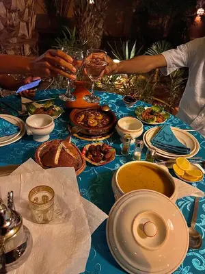 a blue table with plates of food and glasses of wine at Riad le Petit Jardin in Zagora