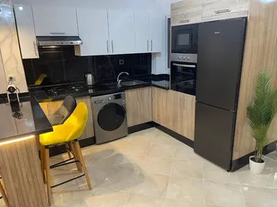 a kitchen with black appliances and a yellow chair at Magnifique appartement moderne (avec Wifi) in Fès