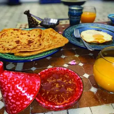 a table topped with plates of food with eggs and pancakes at Kasbah Ifri in Amdnarene
