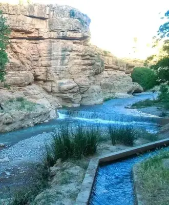 a river with blue water and a rocky cliff at Gite Vanadenite in Midelt