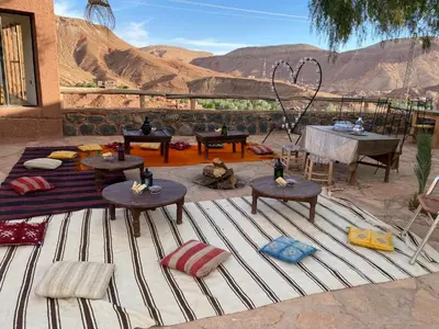 a patio with tables and chairs and a view of the desert at Riad Ecobio in Aït Yous