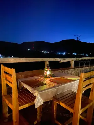 a table and two chairs on a balcony at night at Riad Ecobio in Aït Yous