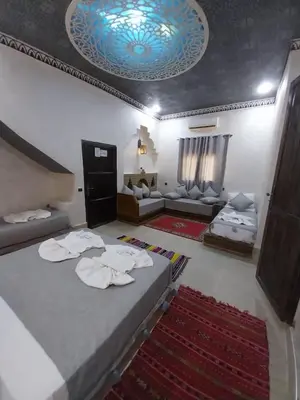 a bedroom with a large bed and a living room at Hotel Cafe Du Sud in Merzouga