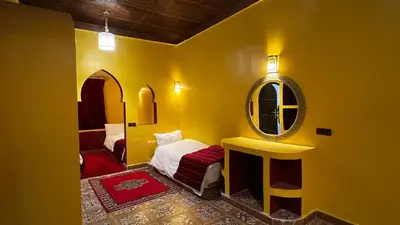 a yellow room with a bed and a mirror at Hotel Cafe Du Sud in Merzouga