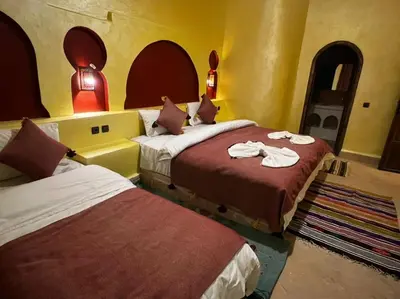 two beds in a room with yellow walls at Hotel Cafe Du Sud in Merzouga
