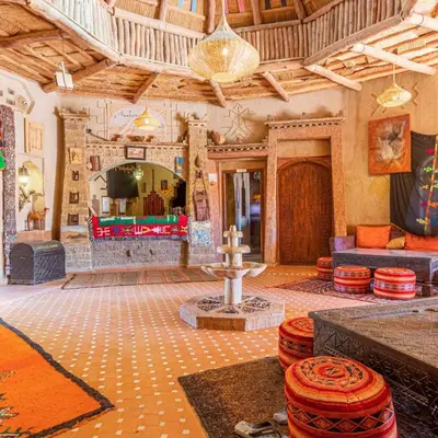a large living room with a fireplace and a table at Hotel Cafe Du Sud in Merzouga