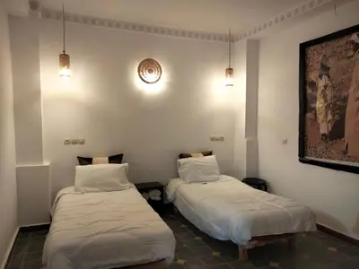 two beds in a room with white walls at Hotel Atlas Gorge Dades in Boumalne