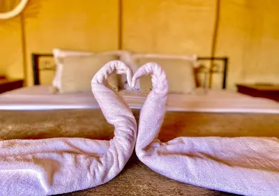 two towels in the shape of a heart on a bed at Titanic Merzouga Camp in Merzouga