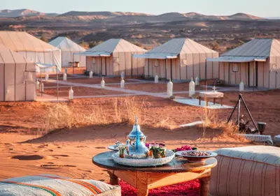 a table in front of some tents in the desert at Titanic Merzouga Camp in Merzouga