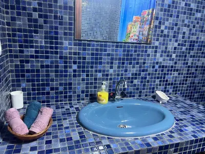 a blue tiled bathroom with a sink and towels at MODERNE APPART PLEIN CENTRE in Fès