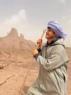 a man holding a stick in the desert at Land of dreams in Nkob