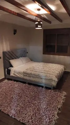 a bedroom with a bed with a rug and a ceiling at Chez karim in Ifrane