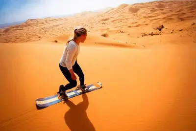 a woman is walking in the desert with aretched at Appartement Hassilabiad-Erg Chebbi in Hassilabied