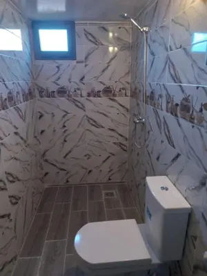 a bathroom with a toilet and a marble wall at Appartement Hassilabiad-Erg Chebbi in Hassilabied