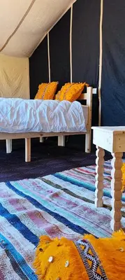 a bedroom with two beds and a rug at Epic Erg Chigaga Desert Camp in El Gouera