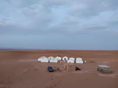 a group of camels in the middle of a desert at Epic Erg Chigaga Desert Camp in El Gouera