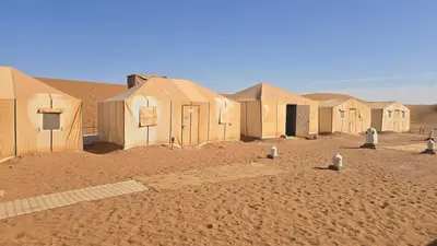 a row of houses in the desert with sand at Epic Erg Chigaga Desert Camp in El Gouera