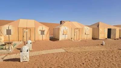 a group of tents in the desert at Epic Erg Chigaga Desert Camp in El Gouera
