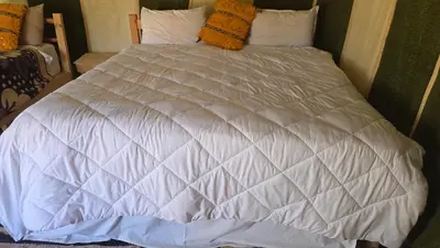a bed with white sheets and pillows at Epic Erg Chigaga Desert Camp in El Gouera