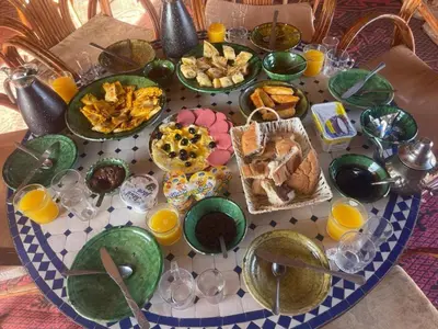 a table with plates of food and glasses of orange juice at Epic Erg Chigaga Desert Camp in El Gouera
